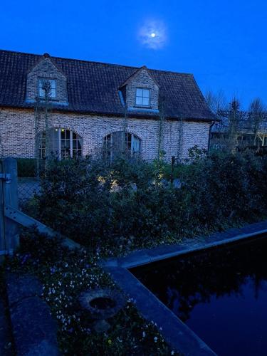 a house with a pond in front of it at night at Domein Den Buiten Bed And Breakfast DnD in Sint-Niklaas