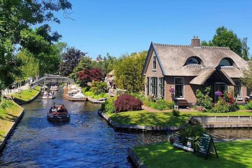 a house on a river with a boat in it at Tiny house Giethoorn in Giethoorn