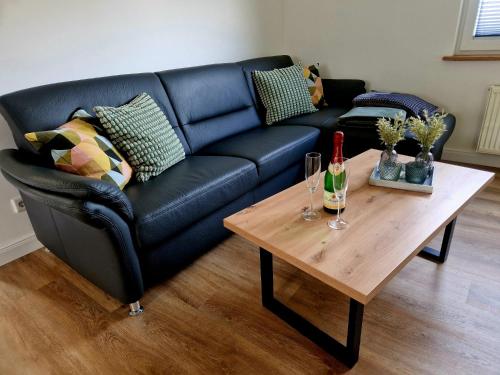 a living room with a black couch and a wooden table at Ferienhaus Nordseeglück im Ferienpark Berumbur in Berumbur