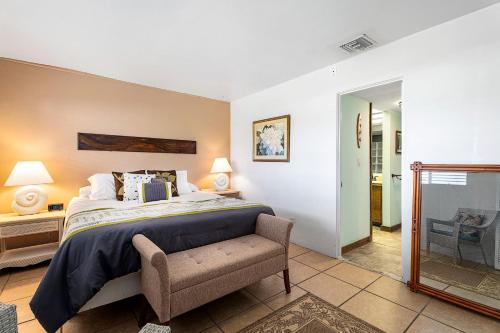 a bedroom with a bed and a chair and a mirror at Casa De Emdeko 230 in Kailua-Kona