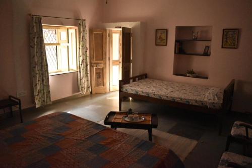 Zimmer mit 2 Betten, einem Tisch und einem Fenster in der Unterkunft Roda House - a boutique homestay in Bikaner in Bikaner