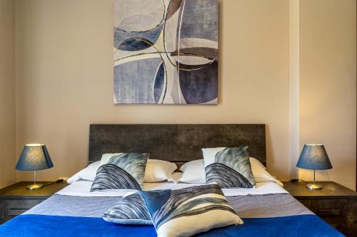a bedroom with a bed with two lamps and a painting at Villetta Desiderio Apartment in Giardini Naxos