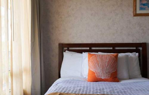 a bed with an orange pillow and white pillows at Gaido's Seaside Inn in Galveston