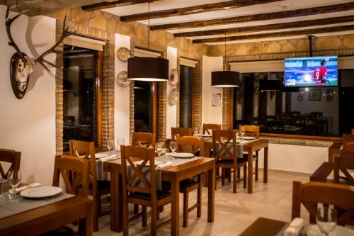 a restaurant with wooden tables and chairs and a flat screen tv at Quinta das Oliveiras Turismo Rural in Fundão