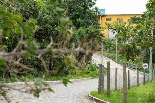 a road with a fence and trees and a building at Hotel BHS in Linhares