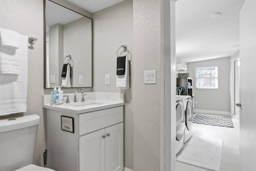 a bathroom with a sink and a washing machine at Tranquil Times a Serene 3BR Close to RJ Stadium with Screened Heated Pool, Outdoor Kitchen and Yard Chess in Tampa