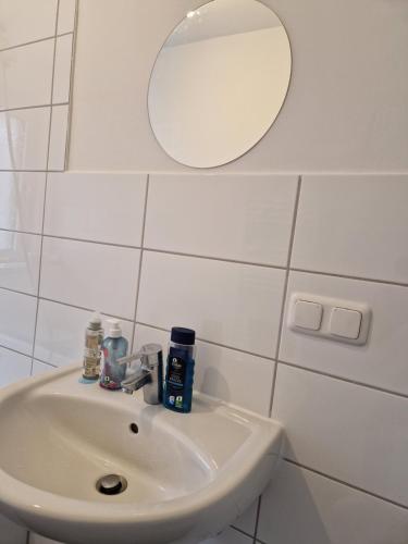 Baño blanco con lavabo y espejo en Abbey homestay en Frankfurt