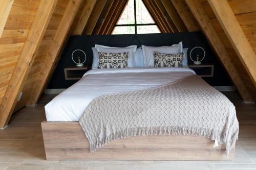 een slaapkamer met een groot wit bed met een houten frame bij GRETEL CHALETS SUIZO in Guatapé