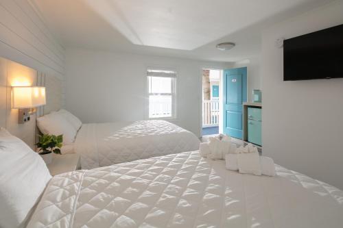 a white bedroom with a bed and a flat screen tv at Lily & Bloom in Myrtle Beach