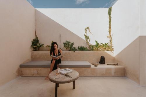 a woman sitting on a bench in a room at Eterna Tulum in Tulum