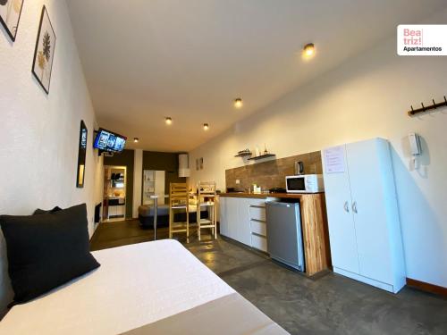 a room with a bed and a kitchen with a refrigerator at Beatriz Apartamentos - Monoambientes in General Pico