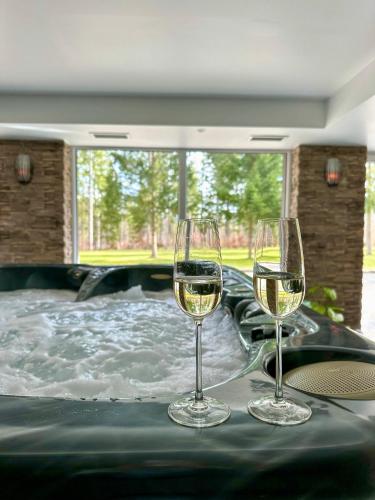two glasses of wine on a table in a hot tub at Chata Tale - Dom Horskej služby in Tale