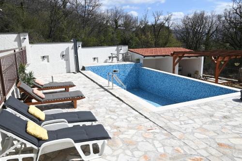 a swimming pool with lounge chairs on a patio at Villa Ella Tvrdos in Trebinje