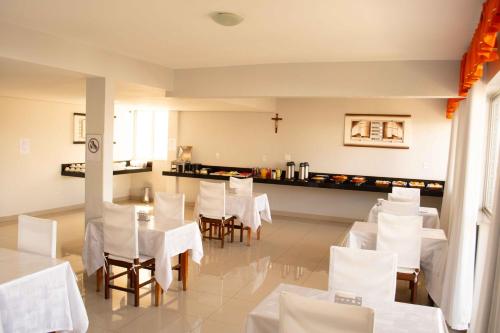 a dining room with white tables and white chairs at Hotel Minas in Três Marias