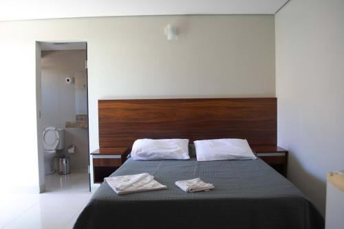 a bedroom with a bed with two towels on it at Hotel Minas in Três Marias