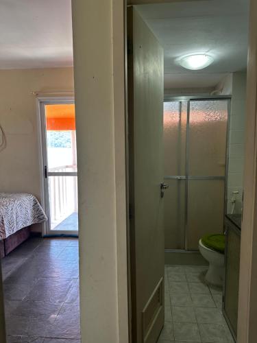 a bathroom with a toilet and a glass shower door at Apartamento em Itacuruça em frente ao mar. in Itacuruçá