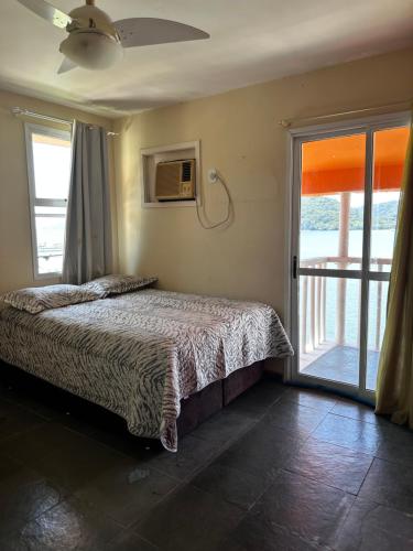 a bedroom with a bed and a sliding glass door at Apartamento em Itacuruça em frente ao mar. in Itacuruçá