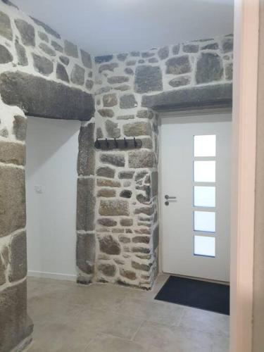 Habitación con pared de piedra y puerta blanca. en Appartement spacieux Saint-Malo, Dinard, Dinan et Dol, en Miniac-Morvan