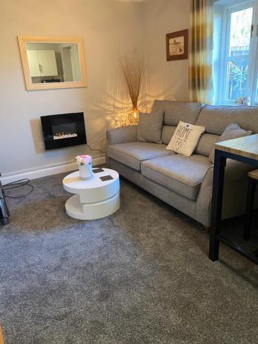 a living room with a couch and a table at Lesbury Lodge - (a 'bijou residence') with hot tub in Alnwick