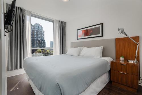 a bedroom with a large white bed and a window at Level Vancouver Yaletown - Seymour in Vancouver