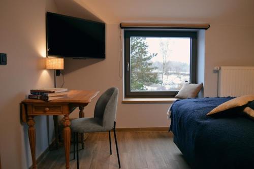 a bedroom with a desk and a bed and a window at La Jardinière in Érezée