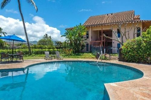 a swimming pool in front of a house at Kauai Makanui by Coldwell Banker Island Vacations in Koloa