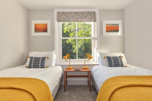 - 2 lits dans une chambre avec fenêtre dans l'établissement House on Beaconsfield spacious seaside home perfect for relaxing with friends or family, à Deal
