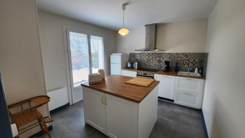 une cuisine avec des armoires blanches et un comptoir en bois dans l'établissement Le gîte du peintre, à Entrains-sur-Nohain