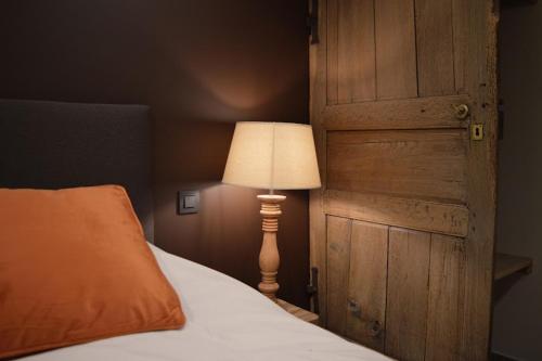 a bedroom with a bed with a lamp next to a door at La Jardinière in Érezée