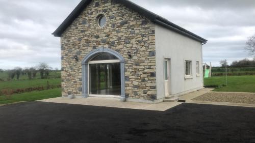 a small white building with a large window at Ard Alainn Lodge, Adorable Setting, scenic views in Grange