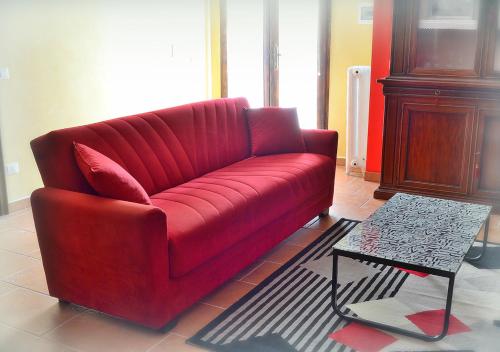 un canapé rouge dans un salon avec une table dans l'établissement Casa Vacanze La Graziella - LA DÉPENDANCE, à Ferrandina