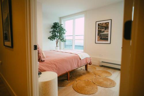NEW Stylish 2BR Condo with Views in North End في هاليفاكس: غرفة نوم مع سرير مع نبات الفخار على الأرض