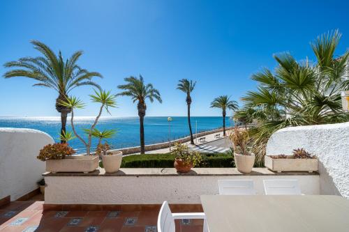 a balcony with palm trees and a view of the ocean at Hauzify I Casa Mirador in L'Ametlla de Mar