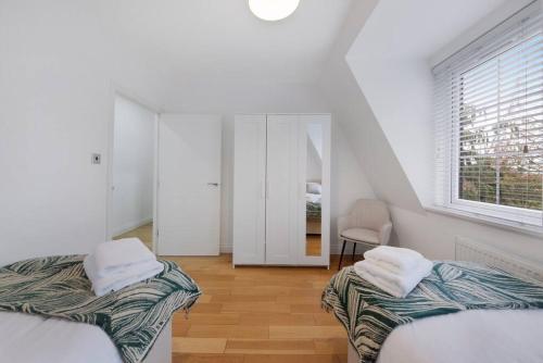 a white room with two beds and a window at Roomy One bed loft apartment in Bishops Stortford