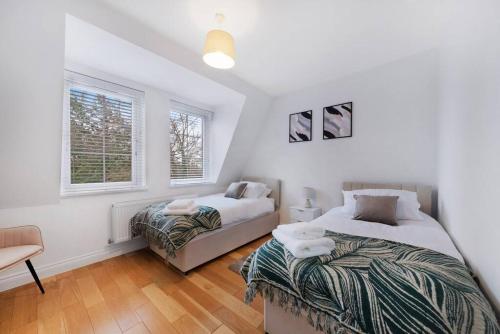ビショップス・ストートフォードにあるRoomy One bed loft apartmentのベッド2台と椅子1脚、窓が2つある寝室