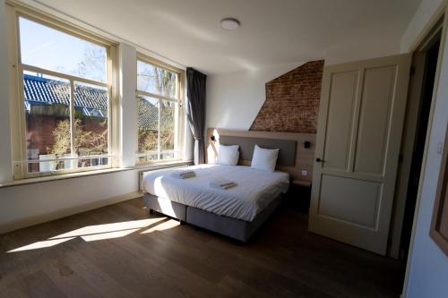 a bedroom with a bed and two large windows at Plantage Hortus Apartments in Amsterdam