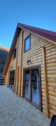 a log cabin with a large glass door at Apartmani Prica in Crni Vrh