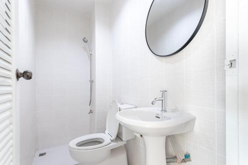 a white bathroom with a toilet and a mirror at Cliff & Beach Villa Phayun in Ban Phayun