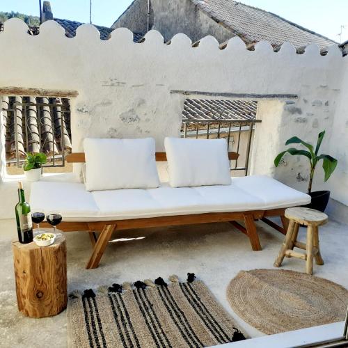 a white bench on a patio with two pillows at Maison Centre Historique Bize Minervois + Terrasse in Bize-Minervois
