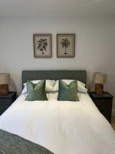 a white bed with two green pillows on it at 39 Teesra House in Plymouth