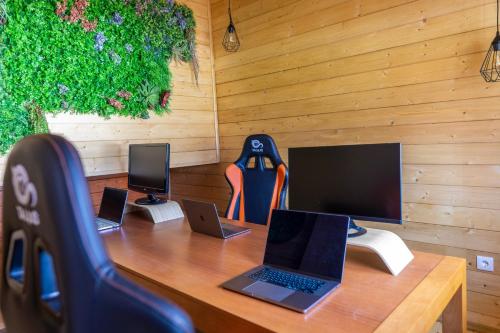 a wooden desk with three laptop computers on it at Coliving The VALLEY Portugal countryside retreat for digital nomads and remote workers - 50 km from Porto in Vale de Cambra