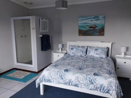 Un dormitorio con una cama blanca y una pintura en la pared en À La Mer - Selfcatering Unit, en Agulhas