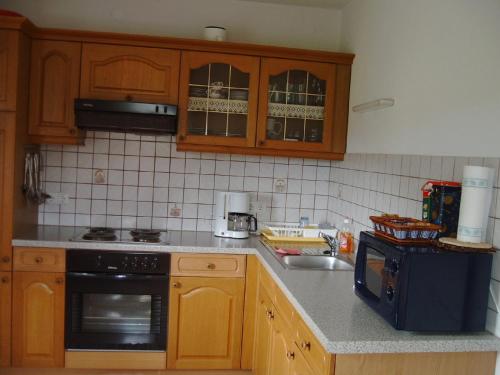a kitchen with wooden cabinets and a sink and a microwave at Ganhör- Fam. Kaar in Wintersdorf