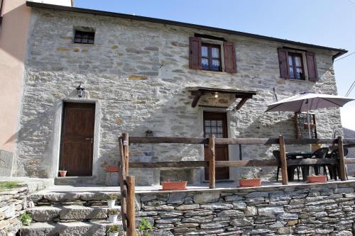 Casa de piedra con valla de madera y sombrilla en Antiche atmosfere... en Borzonasca