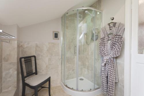 a shower with a glass door and a chair in a bathroom at Rose Cottage in Burnham Thorpe
