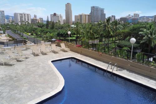 a swimming pool with lounge chairs and a city skyline at Aqua Palms Waikiki in Honolulu