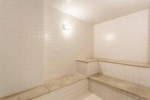 een badkamer met witte betegelde muren en een bank. bij Rio Stay in Rio de Janeiro