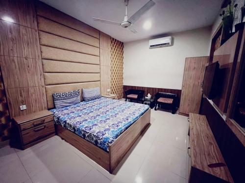 1 dormitorio con 1 cama grande y cabecero de madera en Capital Lodge Gulistan-e-Johar, en Karachi