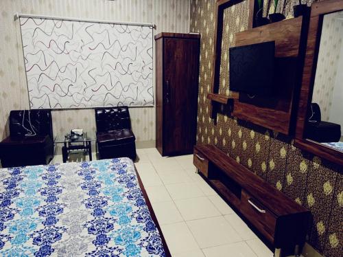 1 dormitorio con 1 cama y TV. en Capital Lodge Gulistan-e-Johar, en Karachi