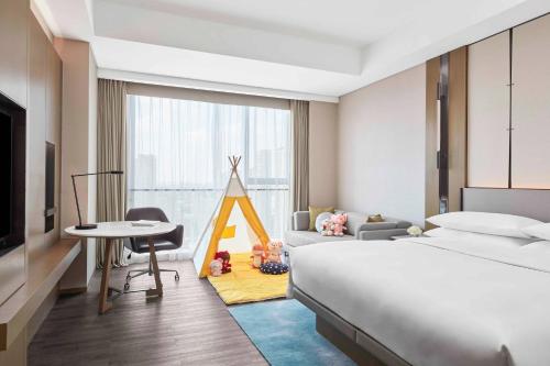 a hotel room with a bed and a desk and a bedroom at Jiaxing Marriott Hotel in Jiaxing